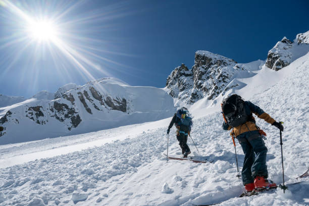 Backcountry skiers cross avalanche slope Backcountry skiers cross avalanche slope on mountain, Tantalus Ranges risky hobbies stock pictures, royalty-free photos & images